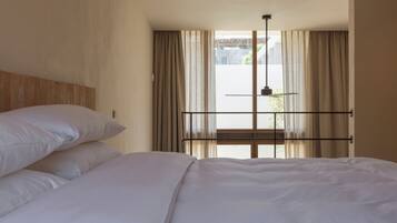 A bedroom with a bed, curtains, a window, and a view of the outside.