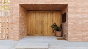 A wooden door with a plaque, a potted plant, and a small step leading to the entrance.