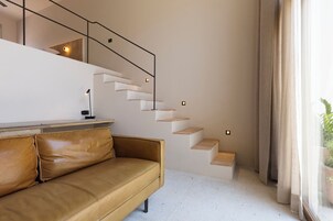 Un interior moderno con una escalera, un sofá de cuero y una ventana con cortinas.