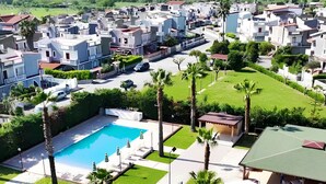 Un quartier résidentiel doté d’une piscine, de palmiers et d’une pelouse bien entretenue.