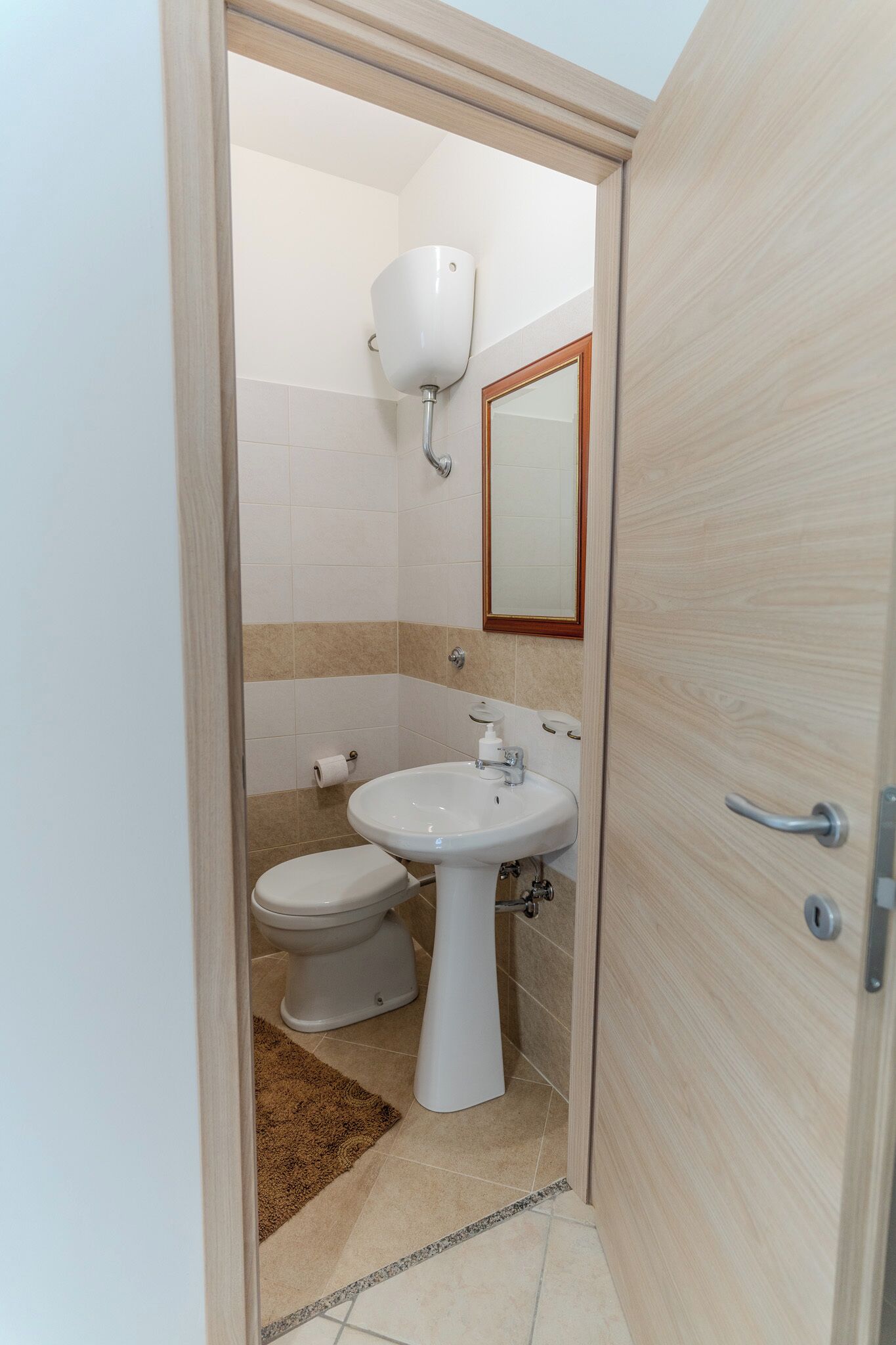 A bathroom with a toilet, sink, and mirror.