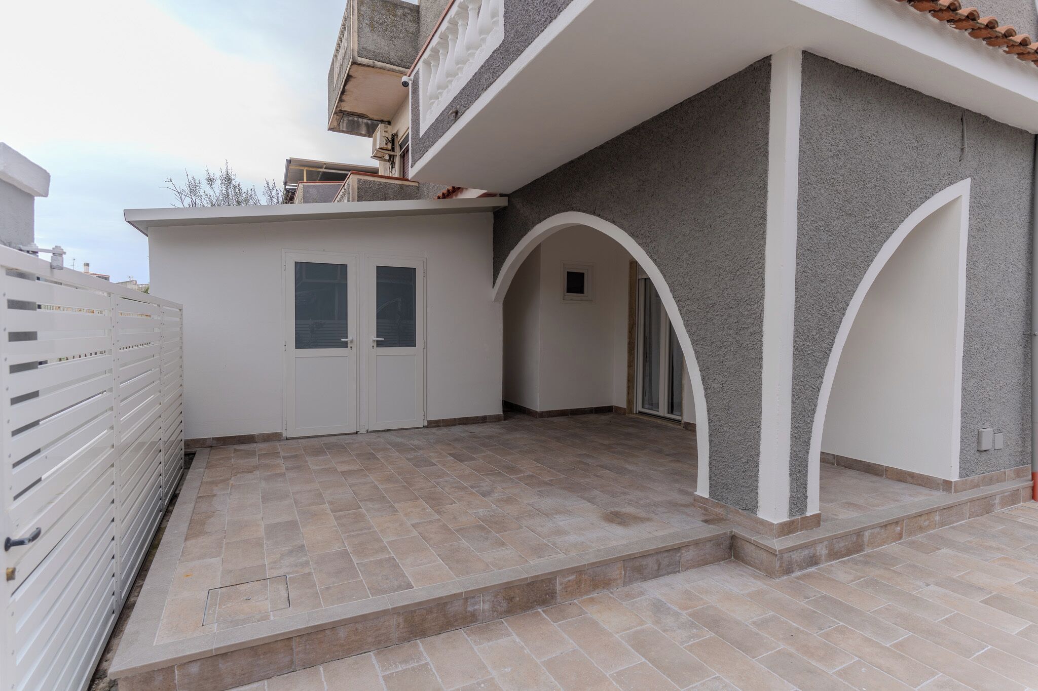 A building with a covered patio area, a white door, and a small window.