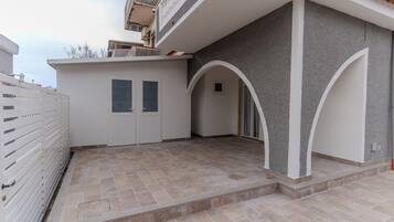 A building with a covered patio area, a white door, and a small window.