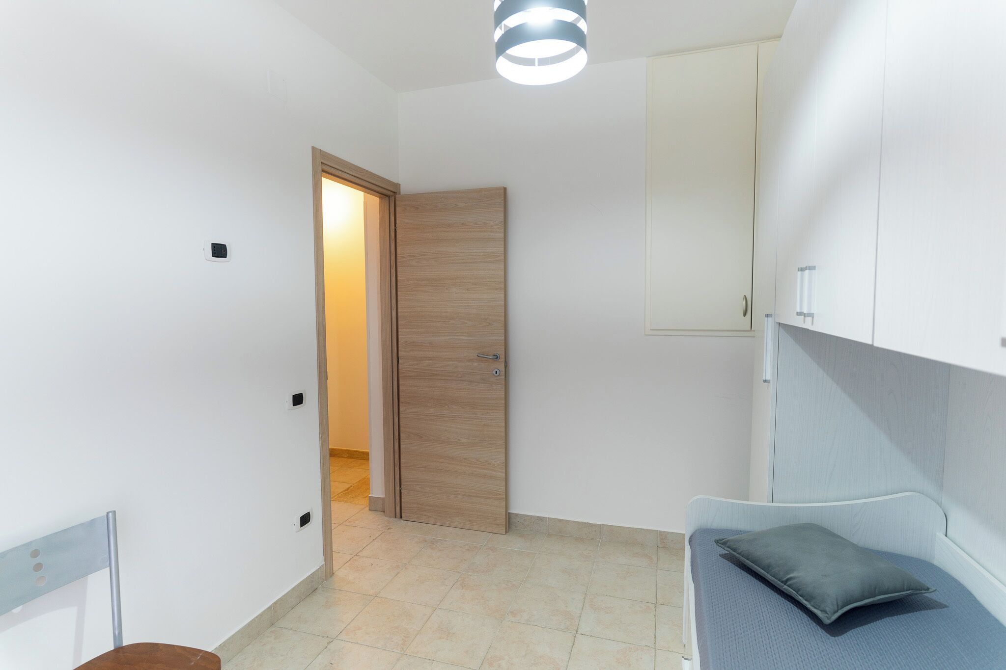 Une pièce avec un lit, une porte et un luminaire.