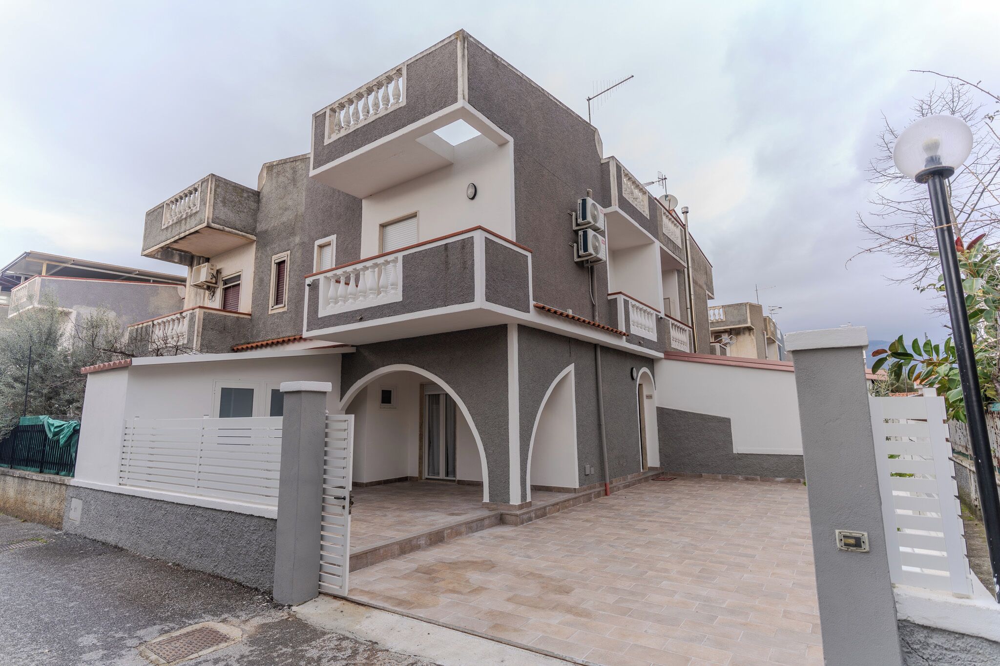 A modern two-story house with a balcony, a garage, and a paved driveway.