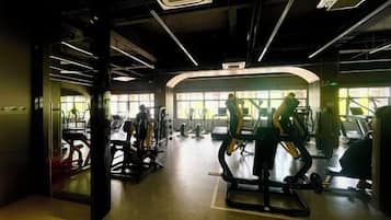 Un gimnasio con máquinas de cardio, equipo de levantamiento de pesas y espejos.