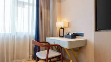 A hotel room with a desk, chair, lamp, and a television.