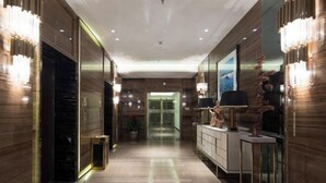 Un vestíbulo de hotel moderno con suelo de mármol, un mostrador de recepción y un espejo grande que refleja el interior.