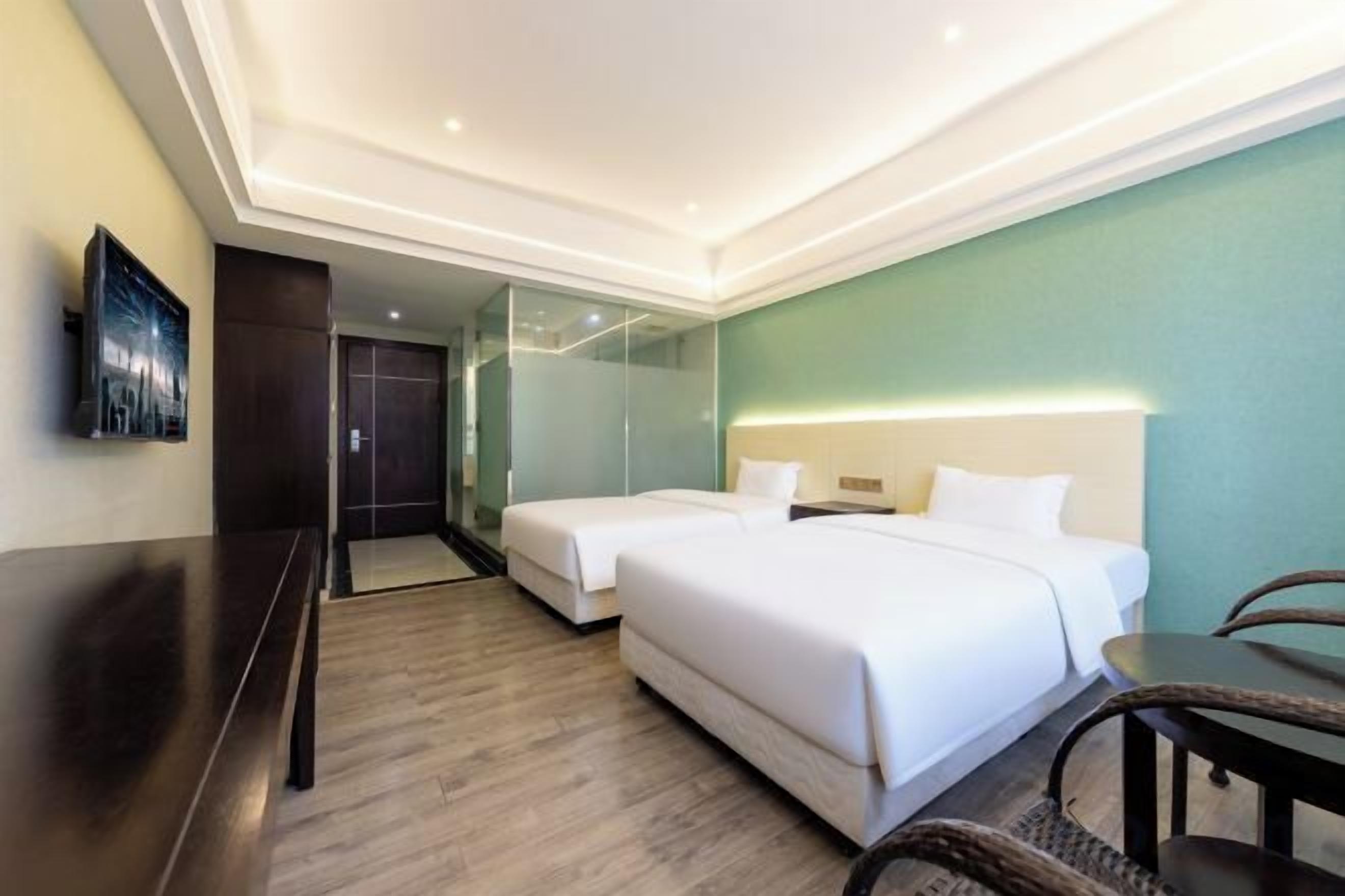 A hotel room with a bed, bedside table, and a TV on the wall.
