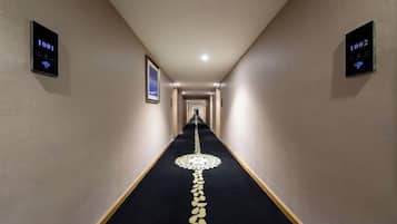A hotel hallway with a carpeted floor, numbered doors, and a framed picture on the wall.