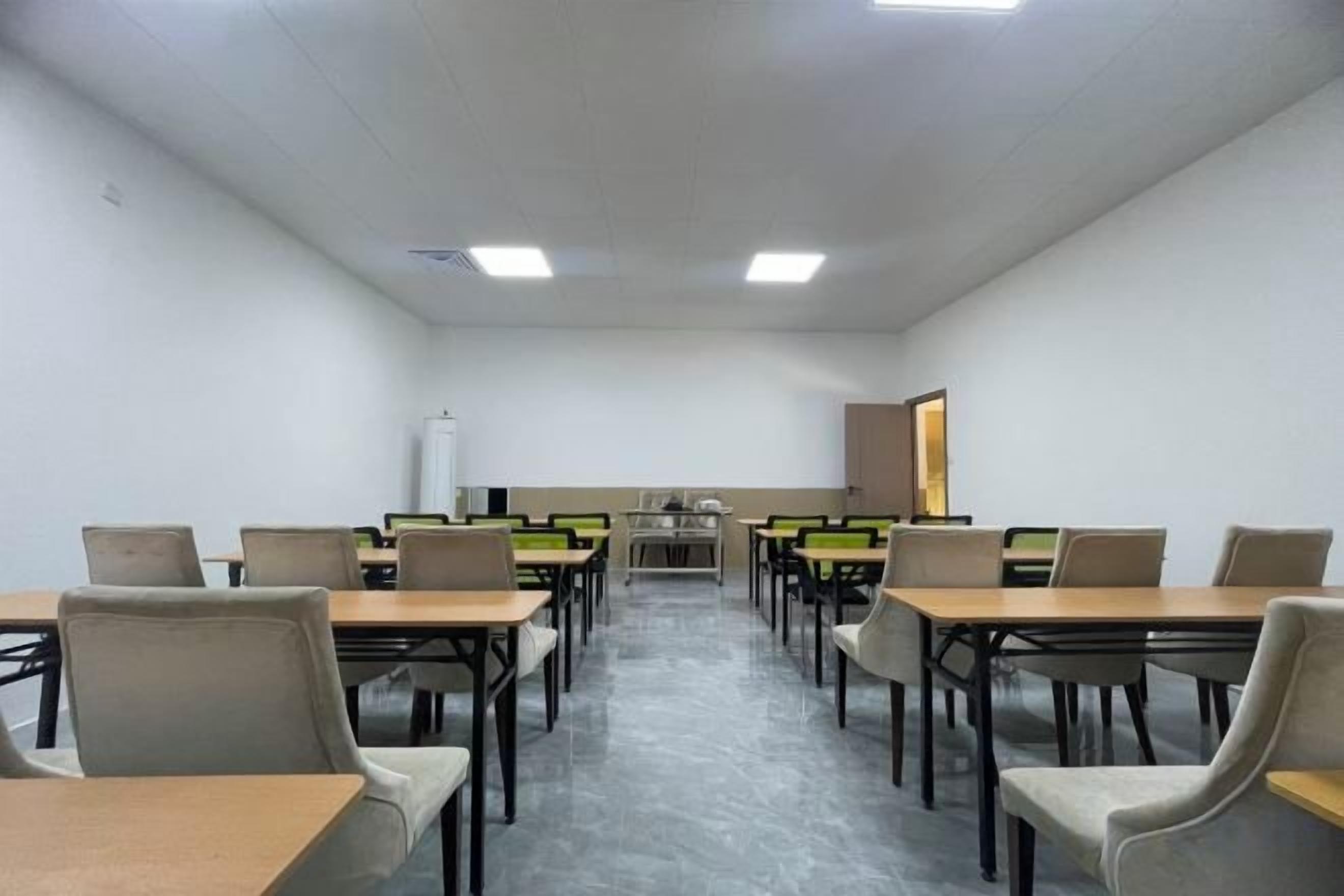Un aula con filas de mesas y sillas, una pizarra y una pantalla para proyector.