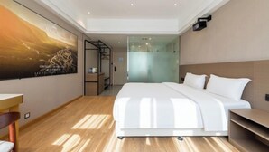 Una habitación de hotel moderna con una cama grande, un escritorio y un muro divisorio de vidrio.