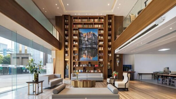 Una biblioteca moderna con estanterías, un cuadro grande y zonas de estar acogedoras.