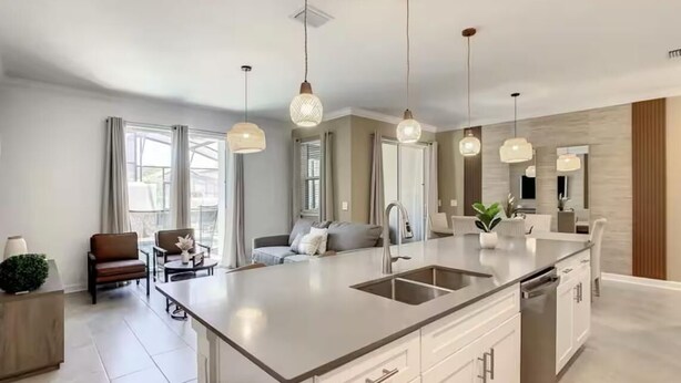 Une cuisine moderne dotée d’un îlot central, de luminaires suspendus et d’un coin repas avec un canapé et des chaises.