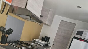 Una cocina compacta con estufa a gas, cafetera y refrigerador.