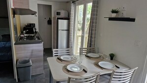 Un comedor con una mesa dispuesta para cuatro personas, un microondas y un refrigerador al fondo.