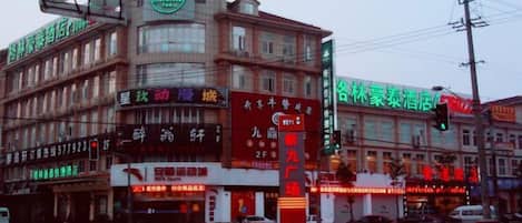 A multi-story building with commercial signage, a traffic light, and a pedestrian crossing.