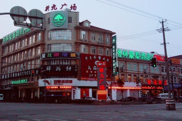 A multi-story building with commercial signage, a traffic light, and a pedestrian crossing.
