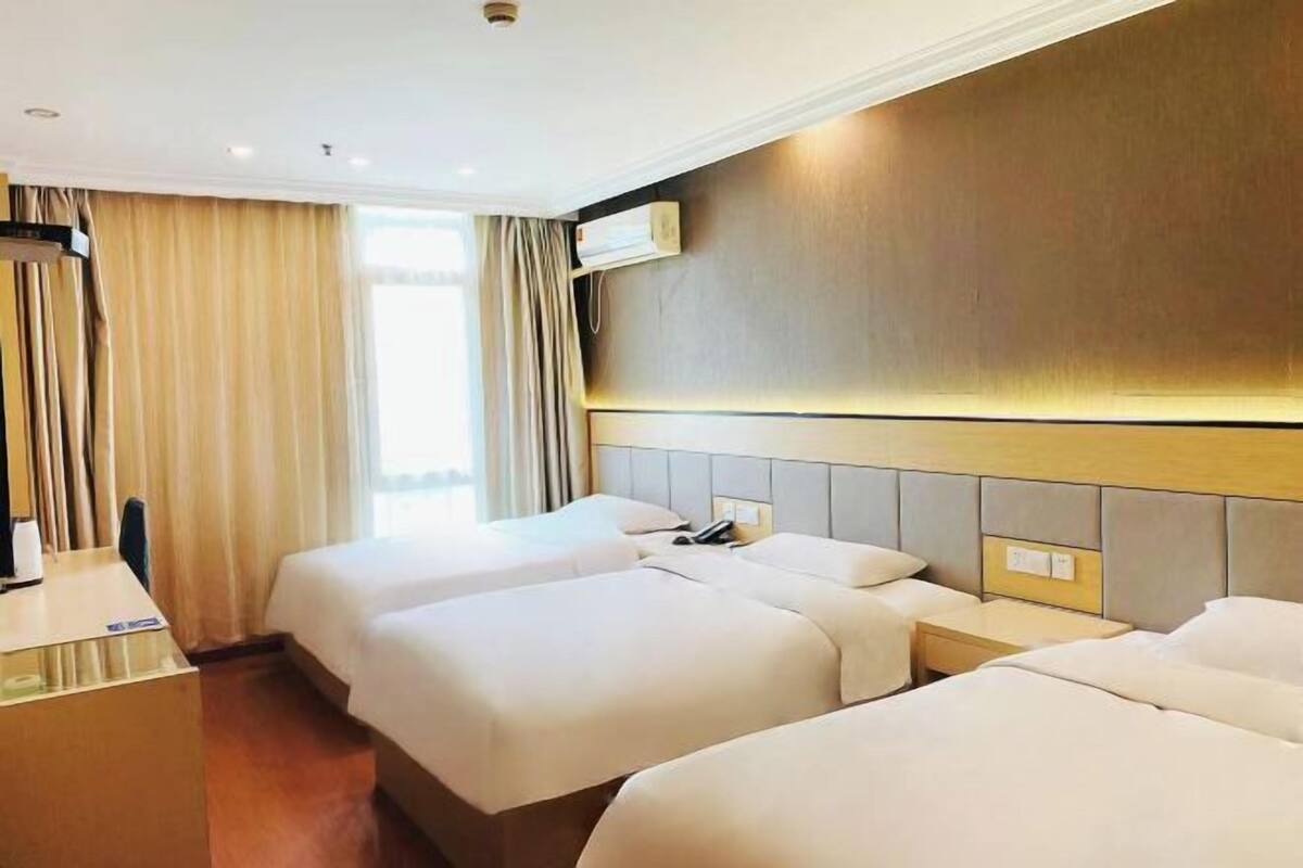 Ein Hotelzimmer mit zwei Betten, einem Schreibtisch und einer Wand-Klimaanlage.