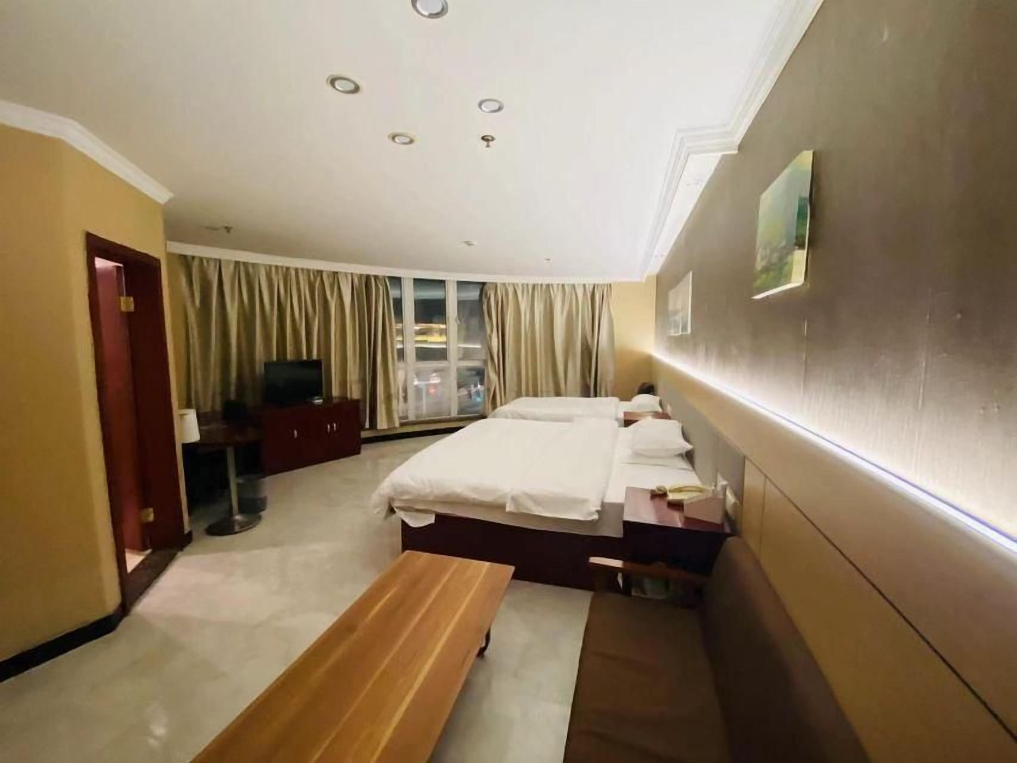 Una habitación de hotel con cama, un banco, un escritorio y una televisión.