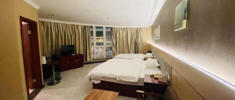 A hotel room with a bed, a bench, a desk, and a television.