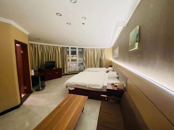 Une chambre d’hôtel avec un lit, une banquette, un bureau et un téléviseur.