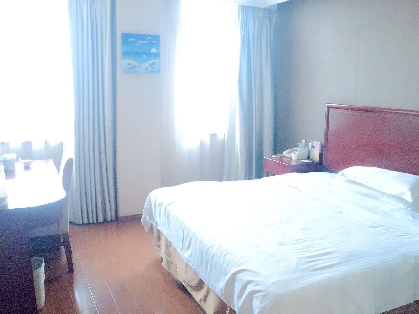 A hotel room with a bed, a desk, and a chair.