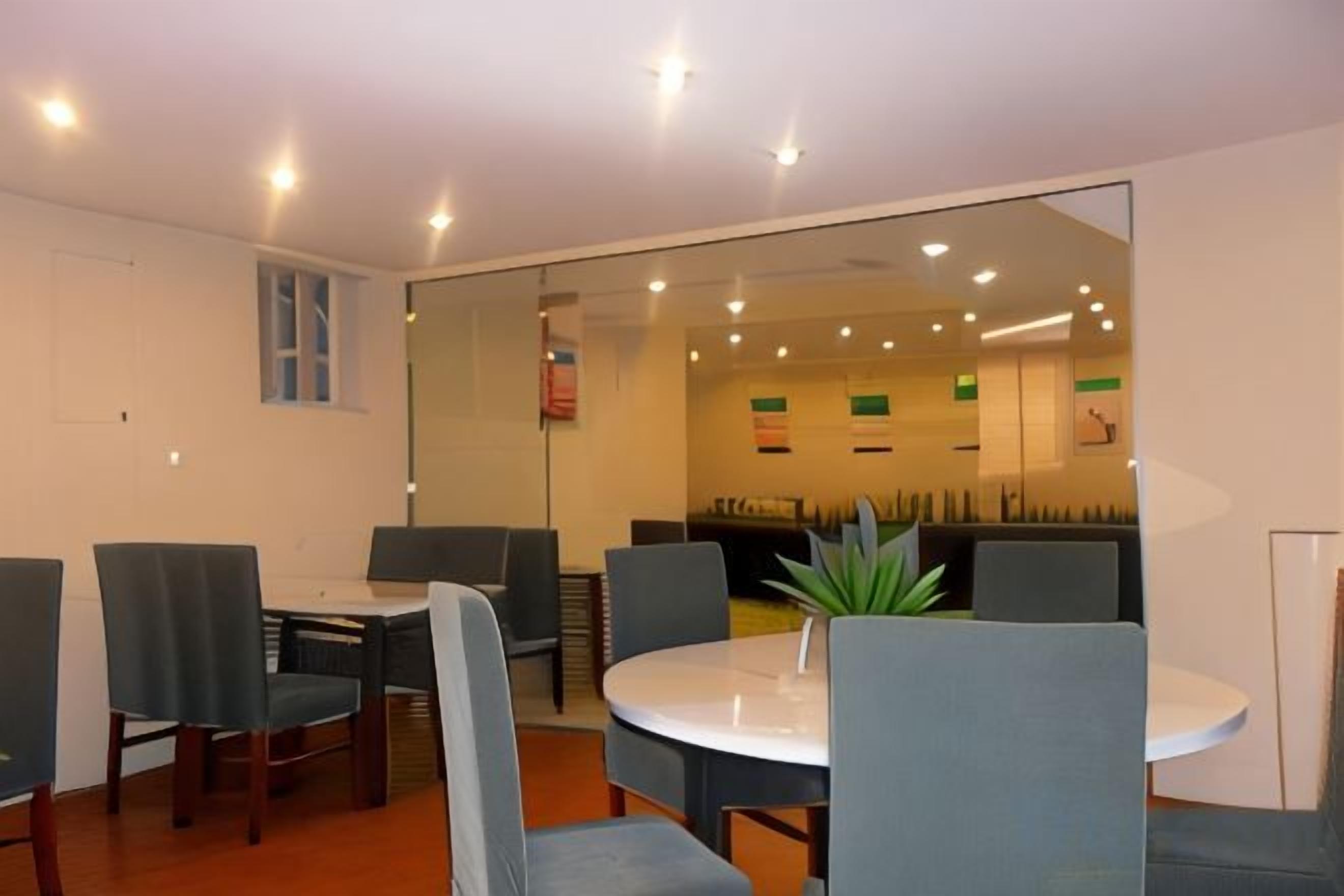 A modern conference room with a glass partition, round table, and several chairs.