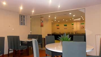 A modern conference room with a glass partition, round table, and several chairs.