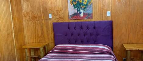 A wooden room with a bed, two nightstands, and a painting of sunflowers.