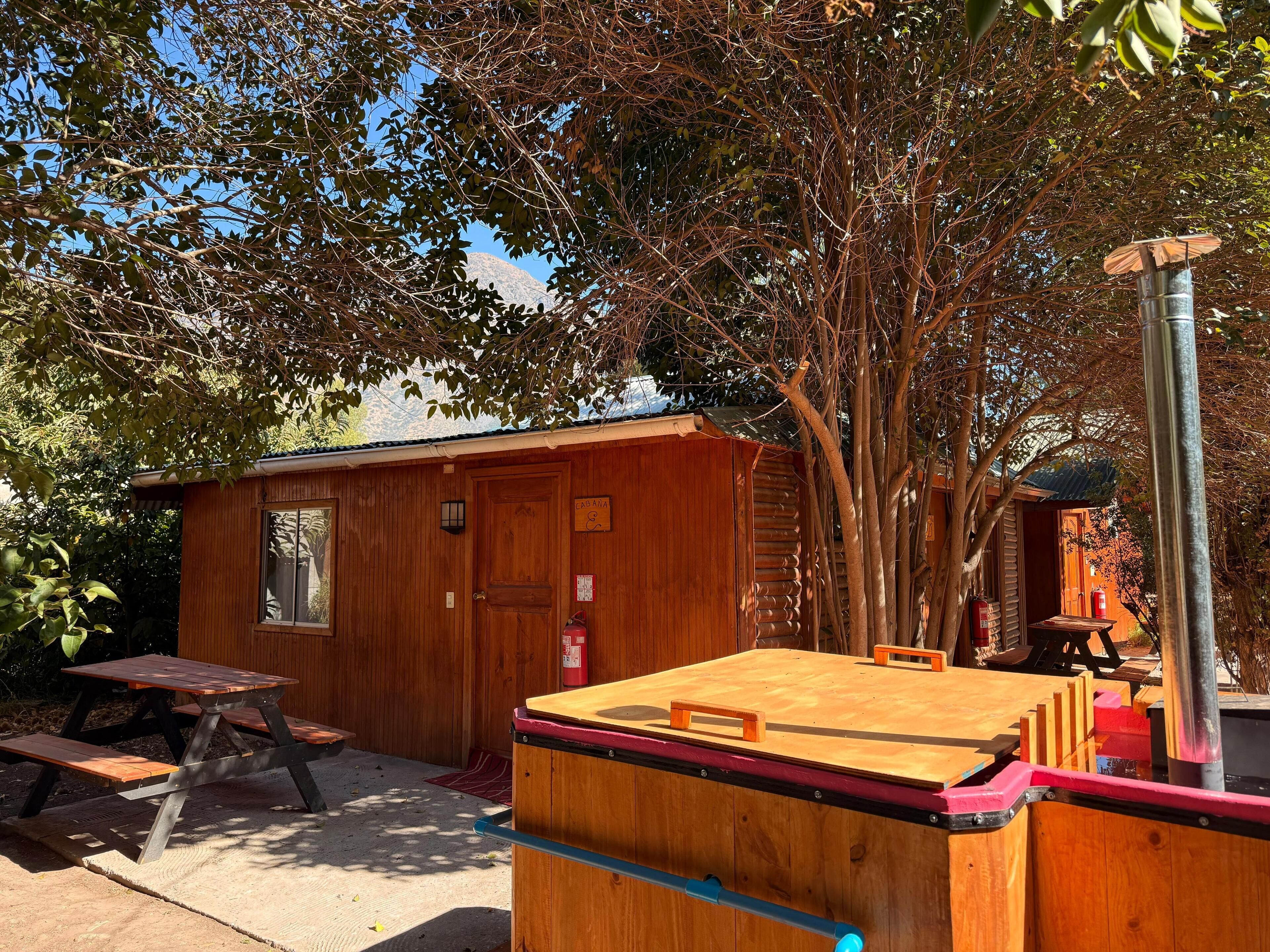 A wooden cabin with a picnic table and a small shed.
