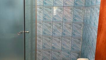 Un baño con cabina de ducha de vidrio, inodoro y azulejos con diseño de mármol azul.