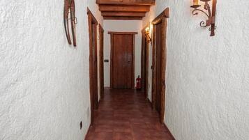 A narrow hallway with wooden doors and a fire extinguisher on the wall.