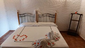 A neatly made bed with a heart-shaped arrangement of rose petals and two white towels folded in a decorative manner. - casa rural la badia (Lucillos)