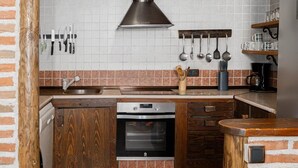 A kitchen with a wooden cabinet, a built-in oven, and a hanging light fixture. - casa rural la badia (Lucillos)