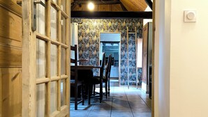 Un corridoio con una porta in legno, pavimento piastrellato e soffitto a vista con travi.