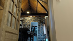 Un corridoio con pavimento piastrellato, soffitto in legno e una porta con pannelli di vetro.