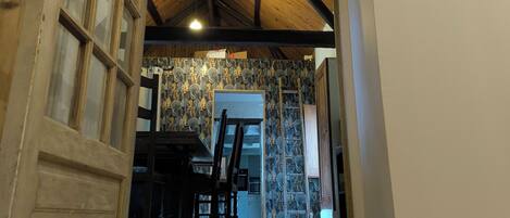 A hallway with a tiled floor, a wooden ceiling, and a door with glass panels.