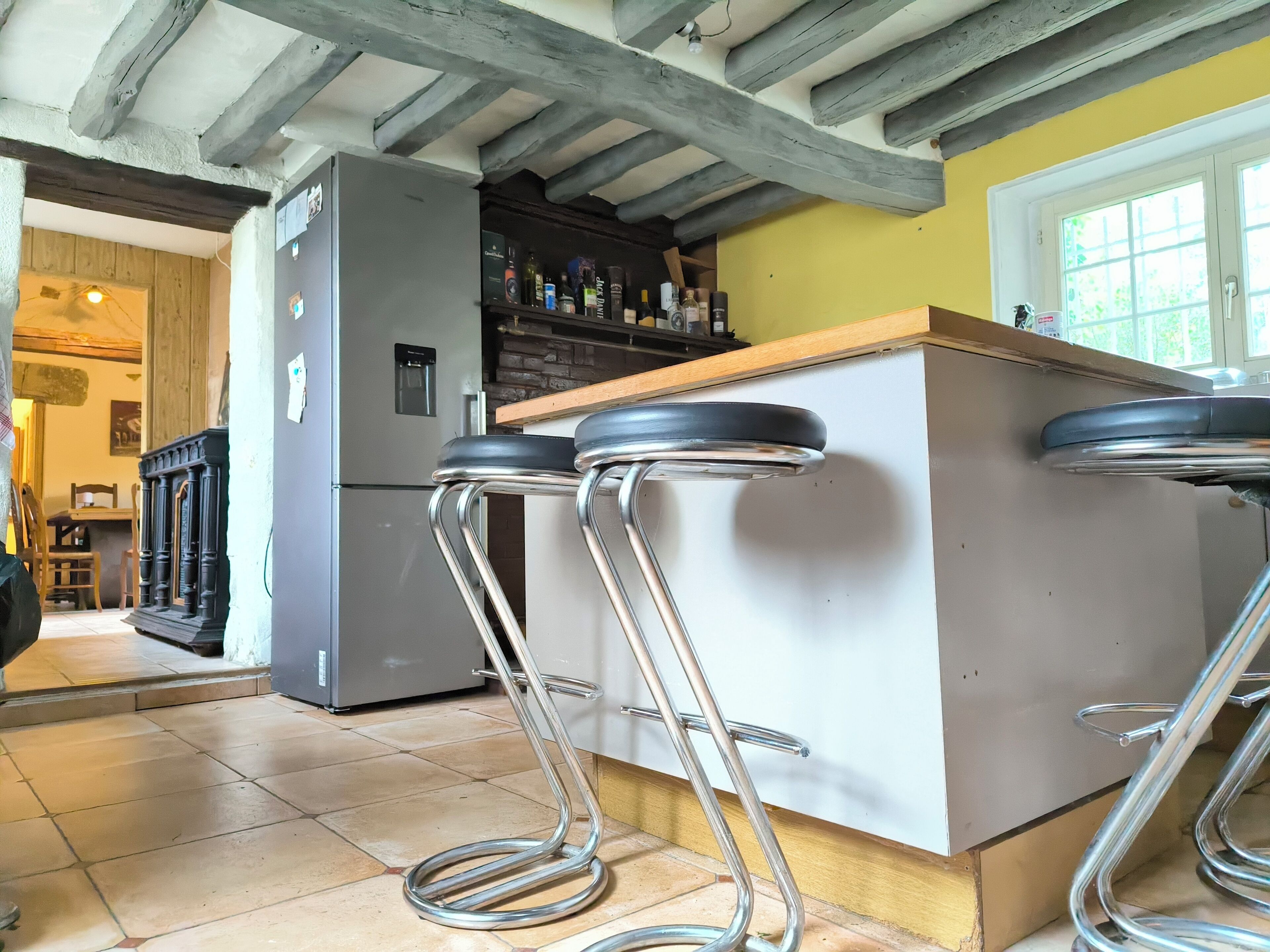 A kitchen with a built-in bar area, a refrigerator, and a wooden dining table with chairs.