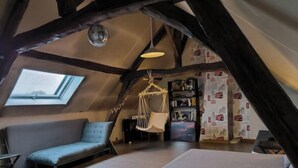 Una camera da letto mansardata accogliente con una finestra sul tetto, un'amaca e una libreria.