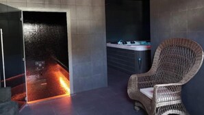 Un'area benessere con una vasca idromassaggio, una poltrona in vimini e un muro rivestito di piastrelle.