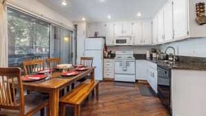 Una cucina moderna con mobili bianchi, un tavolo da pranzo in legno e un'ampia finestra.