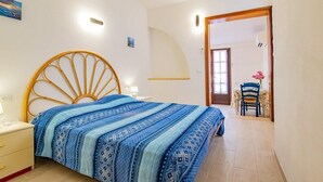 A bedroom with a bed, bedside table, and a chair in the background.