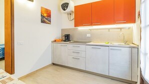 A compact kitchen with a coffee machine, a sink, and orange cabinets.