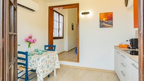 A compact kitchen with a dining area, a mirror, and a painting on the wall.