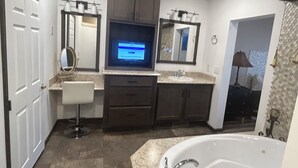 Un baño moderno con televisor integrado, una bañera grande y un tocador con espejo.