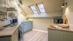 A kitchen with a gas stove, oven, and a sink. There are two skylights and a window. - The Shambles – The Timbered Nest - A premium stay that sleeps 4 guests (York)