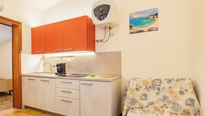 A compact kitchen with a single sink, a coffee machine, and orange cabinets.
