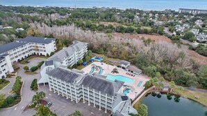 Vista aérea de un resort con un edificio grande, una piscina y un lago.