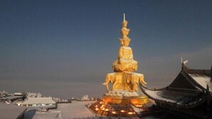 A large, illuminated Buddha statue with a tiered base, surrounded by traditional architecture. - Shangshanju Yangxin Chanjing Hotel (Leshan)